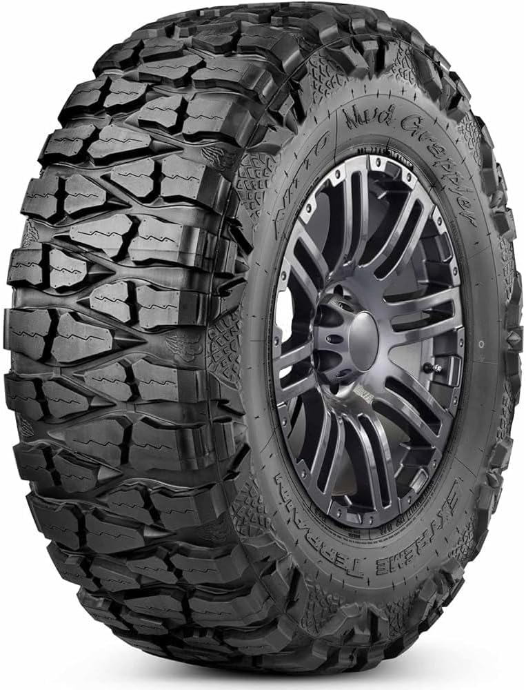 Nitto Mud Grappler extreme terrain tire on a gunmetal alloy wheel, deep tread blocks wrapping over the shoulder into the sidewall lugs
